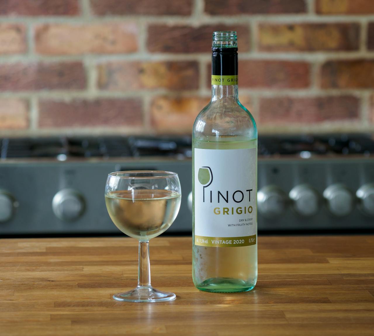Clear Glass Bottle Beside Clear Wine Glass on Brown Wooden Table
