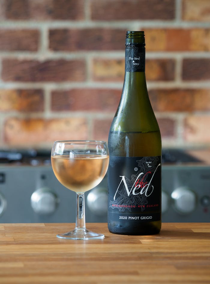 Black and White Labeled Bottle Beside Clear Wine Glass
